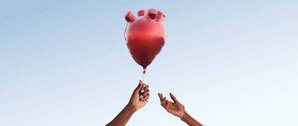 一只手将心形的气球传递给另一只手